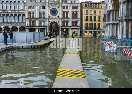 Les gens qui marchent sur les plates-formes élevées au cours d'une acqua alta (haute mer) cas, la Place Saint Marc, Venise, Italie Banque D'Images