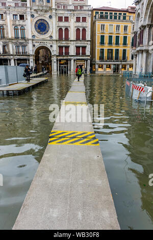 Les gens qui marchent sur les plates-formes élevées au cours d'une acqua alta (haute mer) cas, la Place Saint Marc, Venise, Italie Banque D'Images