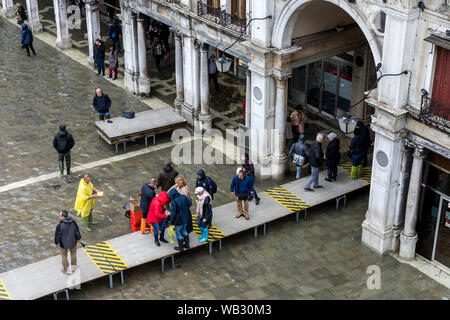 Les gens qui marchent sur les plates-formes élevées au cours d'une acqua alta (haute mer) cas, la Place Saint Marc, Venise, Italie Banque D'Images