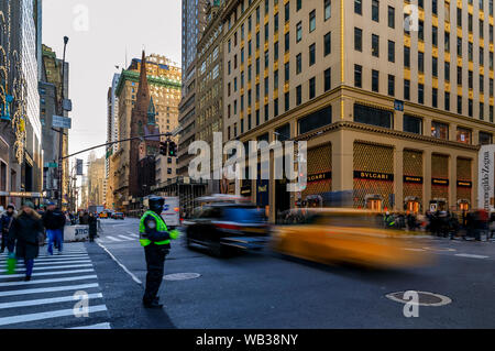 New York, USA - Décembre 07, 2018 : la vitesse des taxis jaunes passé des foules de gens et agent de la circulation à un passage à niveau d'occupation sur la 5e Avenue, Manhattan Banque D'Images