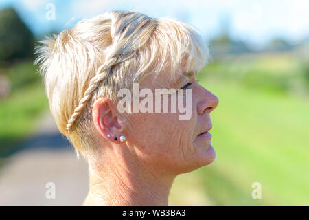 Vue latérale d'une jolie femme blonde avec un sourire amical avec les cheveux courts Banque D'Images