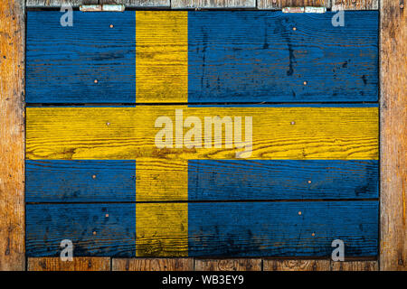 Drapeau national de la Suède sur un mur en bois.La notion de fierté nationale et symbole du pays.Un drapeau peint sur une clôture en bois avec métal Banque D'Images