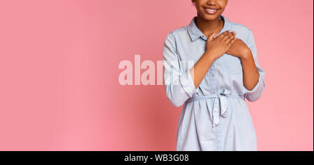 Reconnaissant african girl appuyant sur les mains à la poitrine Banque D'Images