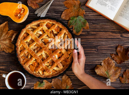 Les mains tenant à la citrouille faits maison. Halloween et Thanksgiving. Maison de vacances bonbons citrouille. Automne Fond en bois, des feuilles sèches, couper le potiron, plateau Banque D'Images