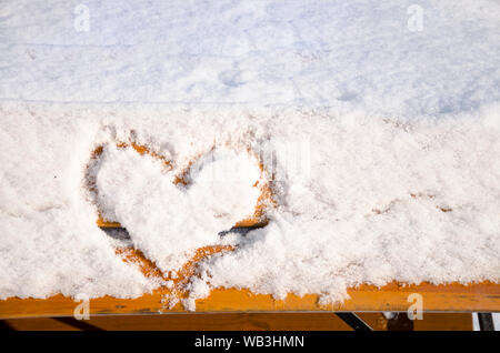 Un coeur écrit dans la neige sur le banc de parc Banque D'Images