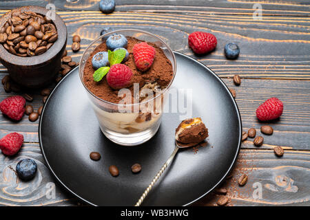 Cuillère à dessert tiramisu classique de pièce avec les bleuets et les fraises dans une coupe en verre sur fond de bois Banque D'Images