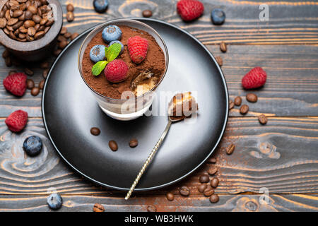 Cuillère à dessert tiramisu classique de pièce avec les bleuets et les fraises dans une coupe en verre sur fond de bois Banque D'Images