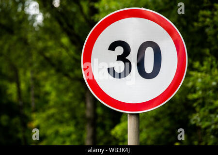 Inscrivez-vous sur la limite de vitesse de 30 kilomètres par heure sur fond vert forêt avec focus sélectif. Fin de symbole de la jeunesse aussi. Orientation horizontale. Banque D'Images