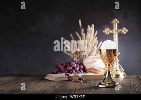 Concept catholique arrière-plan. La Croix, la Sainte Bible et Golden Chalice sur l'autel. Banque D'Images