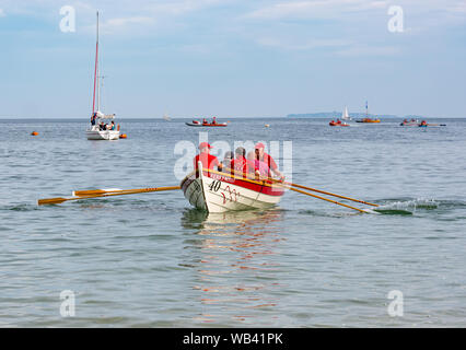 North Berwick, Écosse, Royaume-Uni, 24 août 2019.Des skiffs d'aviron colorés qui participent à la régate de 12 clubs à travers l'Écosse concourent lors d'un week-end chaud de vacances de rive ensoleillé, ramer à 2.5 km autour de l'île Craigleith.Le skiff de St Ayle est un bateau à rames traditionnel de 4 oosées.Photo : le bateau et l'équipe du club d'aviron côtier de Queensferry Banque D'Images