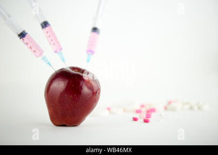 Concept : les droits de l'OGM, manipulation de nature et des fruits empoisonnés. Close-up d'une pomme contaminés par la seringue trois médicaments et en fileté Banque D'Images