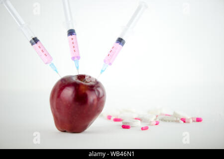 Concept : les droits de l'OGM, manipulation de nature et des fruits empoisonnés. Close-up d'une pomme contaminés par la seringue trois médicaments et en fileté Banque D'Images