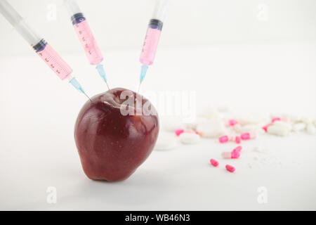 Concept : les droits de l'OGM, manipulation de nature et des fruits empoisonnés. Close-up d'une pomme contaminés par la seringue trois médicaments et en fileté Banque D'Images