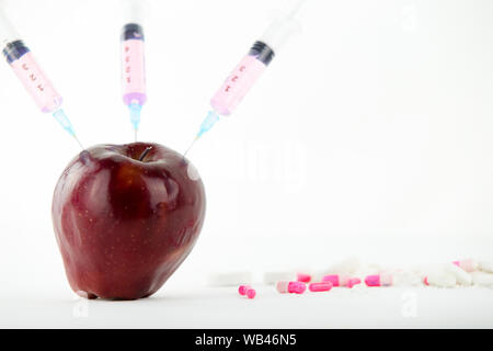 Concept : les droits de l'OGM, manipulation de nature et des fruits empoisonnés. Close-up d'une pomme contaminés par la seringue trois médicaments et en fileté Banque D'Images