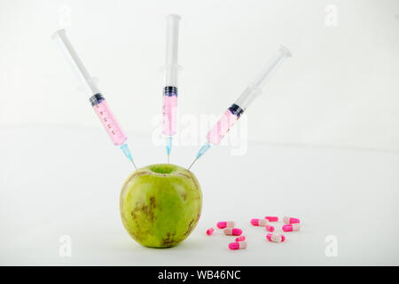 Concept : les droits de l'OGM, manipulation de nature et des fruits empoisonnés. Close-up d'une pomme contaminés par la seringue trois médicaments et en fileté Banque D'Images