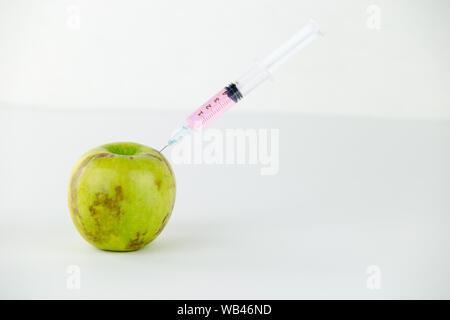 Concept : les droits de l'OGM, manipulation de nature et des fruits empoisonnés. Close-up of an Apple contaminé par une seringue en fileté et white background Banque D'Images