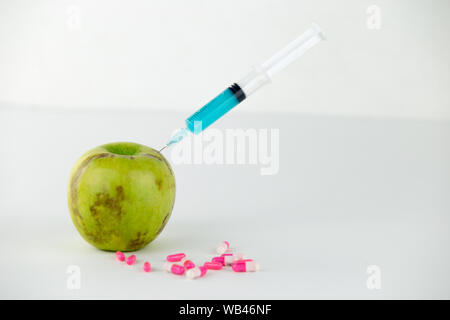 Concept : les droits de l'OGM, manipulation de nature et des fruits empoisonnés. Close-up of an Apple contaminé par une seringue en filetés et des médicaments sur Banque D'Images