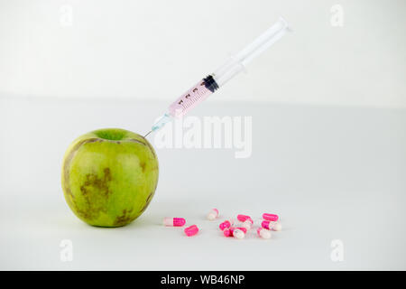 Concept : les droits de l'OGM, manipulation de nature et des fruits empoisonnés. Close-up of an Apple contaminé par une seringue en filetés et des médicaments sur Banque D'Images