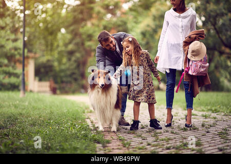 Les parents heureux avec leur fille s'amuse avec le chien dans le parc. Banque D'Images