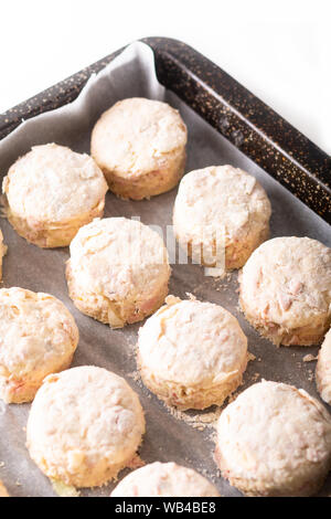 Concept de l'alimentation de la pâte au beurre salé fait maison, jambon et fromage scones avant cuisson sur fond blanc Banque D'Images