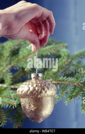 Acorn verre décoration de Noël dans la main contre le mur de couleurs vives. Vacances décoration d'arbre de Noël Banque D'Images