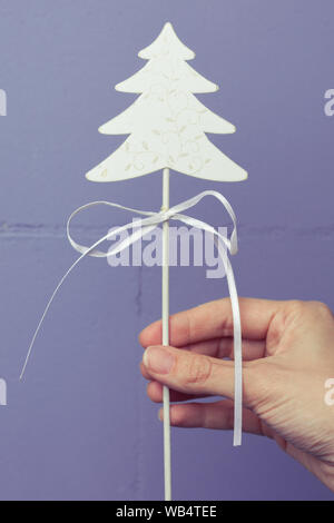 Décoration de Noël en bois blanc dans la main contre le mur de couleurs vives. Décoration de fêtes décoration d'arbre de Noël Banque D'Images