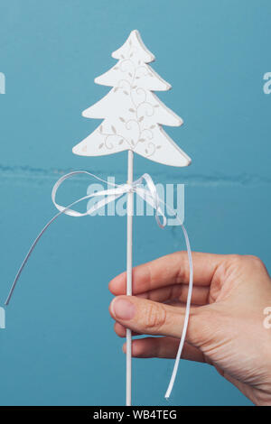 Décoration de Noël en bois blanc dans la main contre le mur de couleurs vives. Décoration de fêtes décoration d'arbre de Noël Banque D'Images