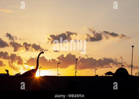 Sauropode dino venir à la ville. Une silhouette de dinosaure herbivores dans la ville avec un ciel spectaculaire derrière. Banque D'Images