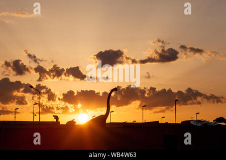 Sauropode dino venir à la ville. Une silhouette de dinosaure herbivores dans la ville avec un ciel spectaculaire derrière. Banque D'Images