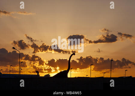 Sauropode dino venir à la ville. Une silhouette de dinosaure herbivores dans la ville avec un ciel spectaculaire derrière. Banque D'Images