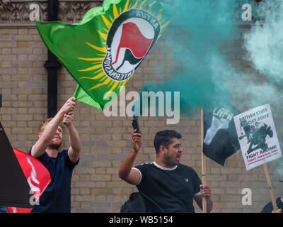 Londres, Royaume-Uni. 24 août 2019. Anti-fascistes tenir des drapeaux et des torches comme ils s'opposent à une protestation à la BBC par Tommy Robinson partisans qui affirment qu'il est en prison pour le journalisme. Il a été condamné à 9 mois pour 3 infractions à l'extérieur de Leeds Crown Court qui pourrait avoir mené à l'effondrement d'un gang de toilettage, d'essai et a déjà été condamné pour violence familiale, financière et de l'immigration aux fraudes, possession de drogue et l'ordre public. La police deux groupes séparés. Robinson partisans ont été rejoints plus tard par marcheurs d'Trafalgar Square, et un groupe plus important de résister au racisme sont venues rejoindre Antifa. Peter Banque D'Images