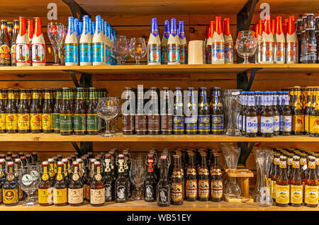 Les étagères avec une collection de bouteilles de bière belge et diverses marques avec leur verre spécifique dans le centre-ville de Bruges. Banque D'Images