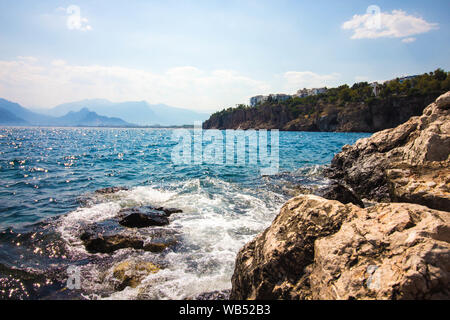 Des vagues d'eau de mer se laver les pierres. La rive du lac, les montagnes et les pierres sont des pierres. Maisons d'habitation ont été construites sur le rocher. Banque D'Images