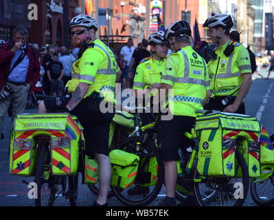 Quatre cyclistes de St John Ambulance conduit le Manchester, UK, LGBT Pride Parade le 24 août 2019, par l'intermédiaire de centre-ville de Manchester. Plusieurs milliers de personnes étaient alignés sur la rue pour regarder le défilé. Banque D'Images