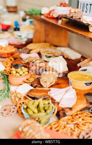 gros plan de moutarde, saucisses en tranches, concombres marinés, olives et biscuits sur une planche de bois Banque D'Images