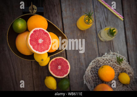 Vue de dessus les agrumes frais en échelle vintage et plusieurs des oranges, citrons, pamplemousse, citron vert et bouteilles de limonade sur la vieille table en bois rustique. Detox Banque D'Images