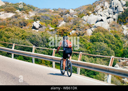 Homme de rouler à vélo sur la route, sur des pierres à Capo Testa à la mer Méditerranée en Santa Teresa Gallura province en Sardaigne, île d'Italie. Scenery Banque D'Images