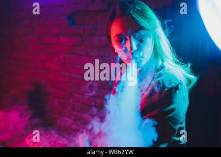 elfbar nachfüll pod läuft aus Femme fume une e-cigarette allongé sur le lit dans la chambre. Concept du  fumeur Vaping Photo Stock