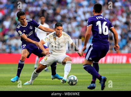 Madrid, Espagne. Août 24, 2019. Real Madrid's James Rodriguez (C) est en concurrence avec l'Valladolid Enes Unal (L) au cours d'un match de football ligue espagnol entre le Real Madrid et Valladolid à Madrid, Espagne, le 24 août, 2019. Crédit : Edward F. Peters/crédit : Xinhua Xinhua/Alamy Live News Banque D'Images