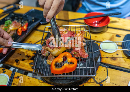 Les gens de la viande et faire griller le poivron sur un charbon cuisinière Banque D'Images