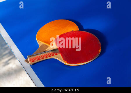 Close-up of orange et rouge deux raquettes de tennis de table allongé sur un tableau bleu Banque D'Images