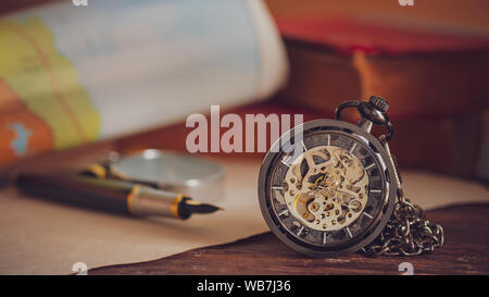 Montre de poche avec de vieux livres et stylo avec carte papier sur la table par la fenêtre. Concept de planification de voyage. Banque D'Images