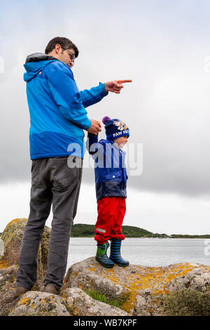 Royaume-uni, Angleterre, Îles Scilly, Tresco, New Grimsby, Port, père et fils debout sur les rochers à côté du quai Banque D'Images