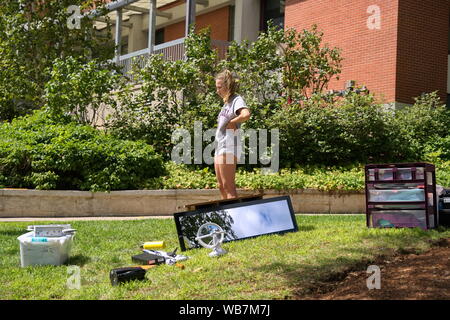 Storrs, CT USA. Aug 2019. Seule femme coed avec toutes les fournitures sur la pelouse en prenant une pause de déménagement dans son nouveau dortoir. Banque D'Images