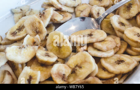 Chips de banane dans un bol de petit-déjeuner blanche avec une cuillère Banque D'Images