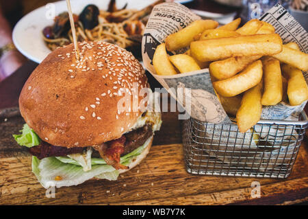 Burger et frites / plaquettes dans un panier sur une planche en bois dans un restaurant Banque D'Images