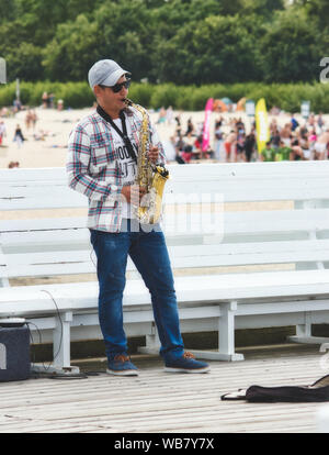 Sopot / Pologne - 3 août 2019 : un saxophoniste sax soufflant le musicien ambulant pour de l'argent sur la jetée Banque D'Images