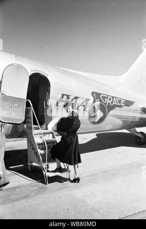 Femme tenant un manteau de fourrure et sombrero à bord d'un American-Grace Airways (Pan) à la position de l'avion Panagra Buenos Aires, Argentine. Banque D'Images