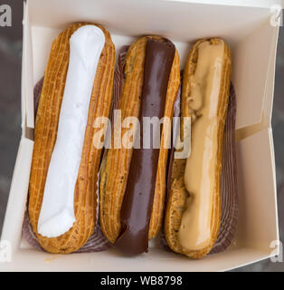 Éclairs colorés dans la boîte. Pose à l'intérieur de cases blanches éclairs. Les gâteaux avec Eclair ébouillanté Carmel café crème et beurre. Banque D'Images