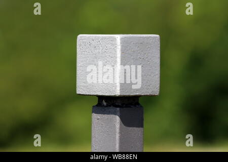 Cube de métal gris clair monté sur le dessus d'une clôture en fer forgé jardin local sur jour d'été chaud et ensoleillé Banque D'Images